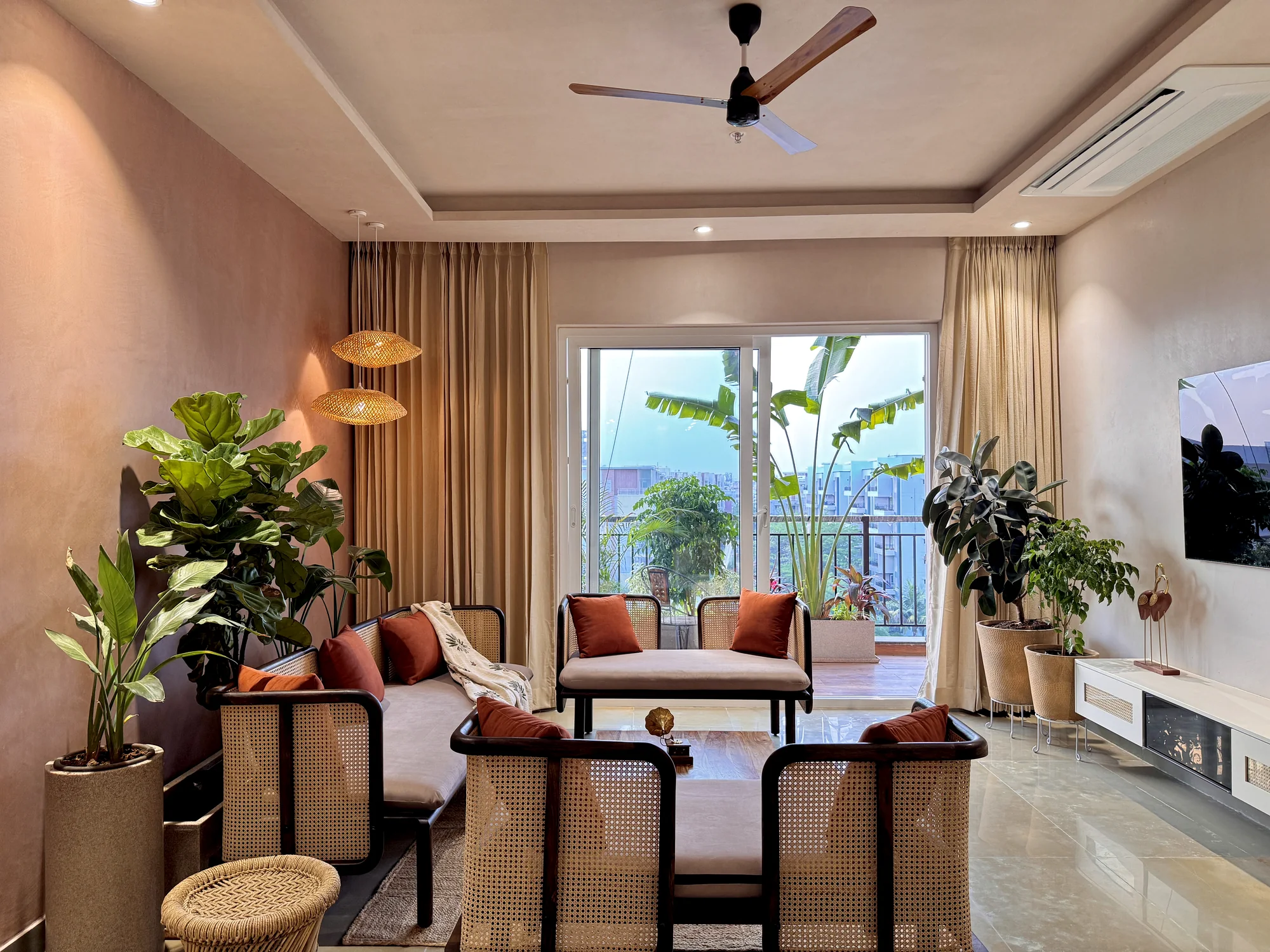 Contemporary living room with indoor plants and a view to a planted balcony, photographed for a biophilic interior design article