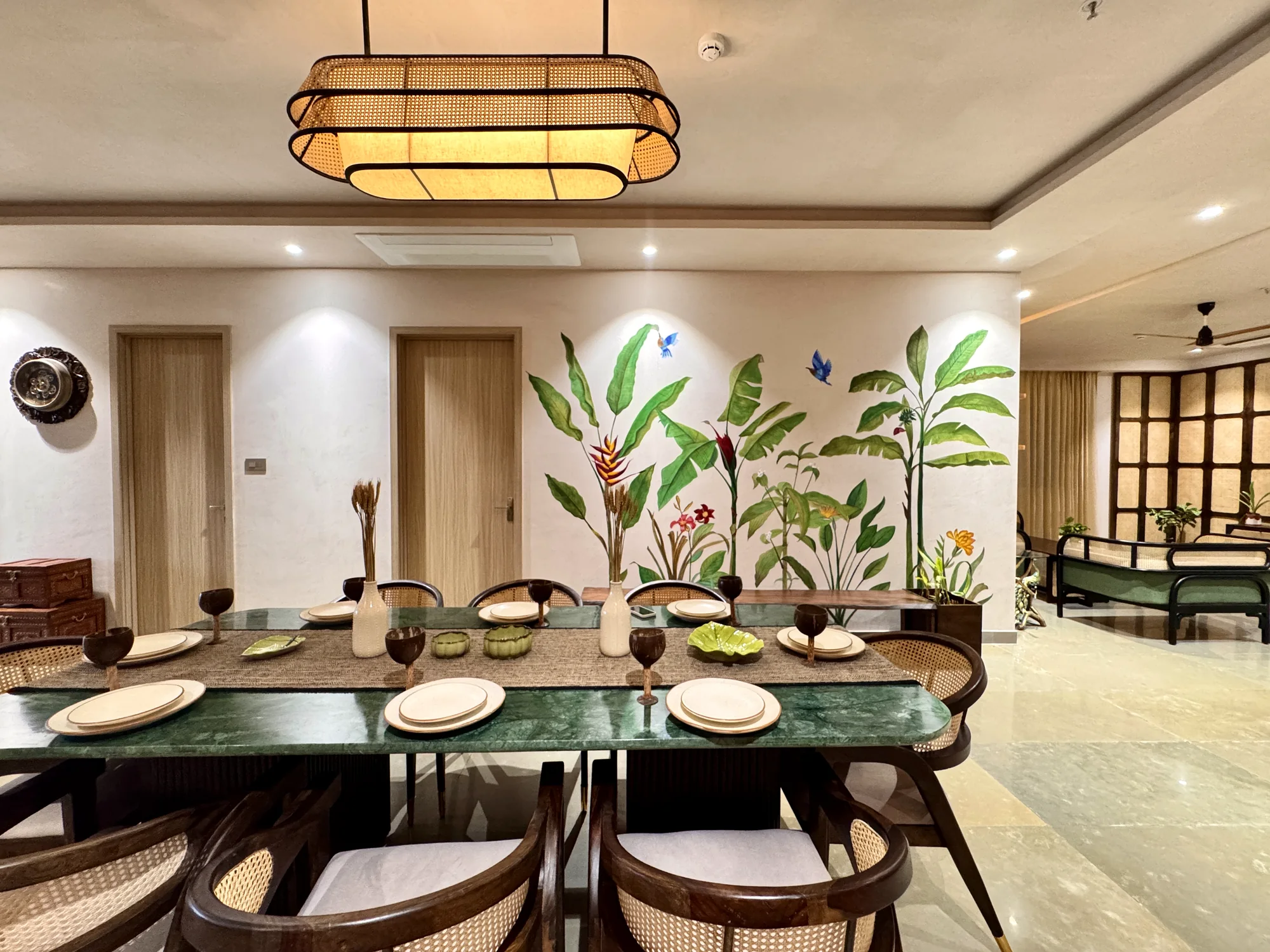 Dining space with a long table, botanical wall treatment and indoor greenery